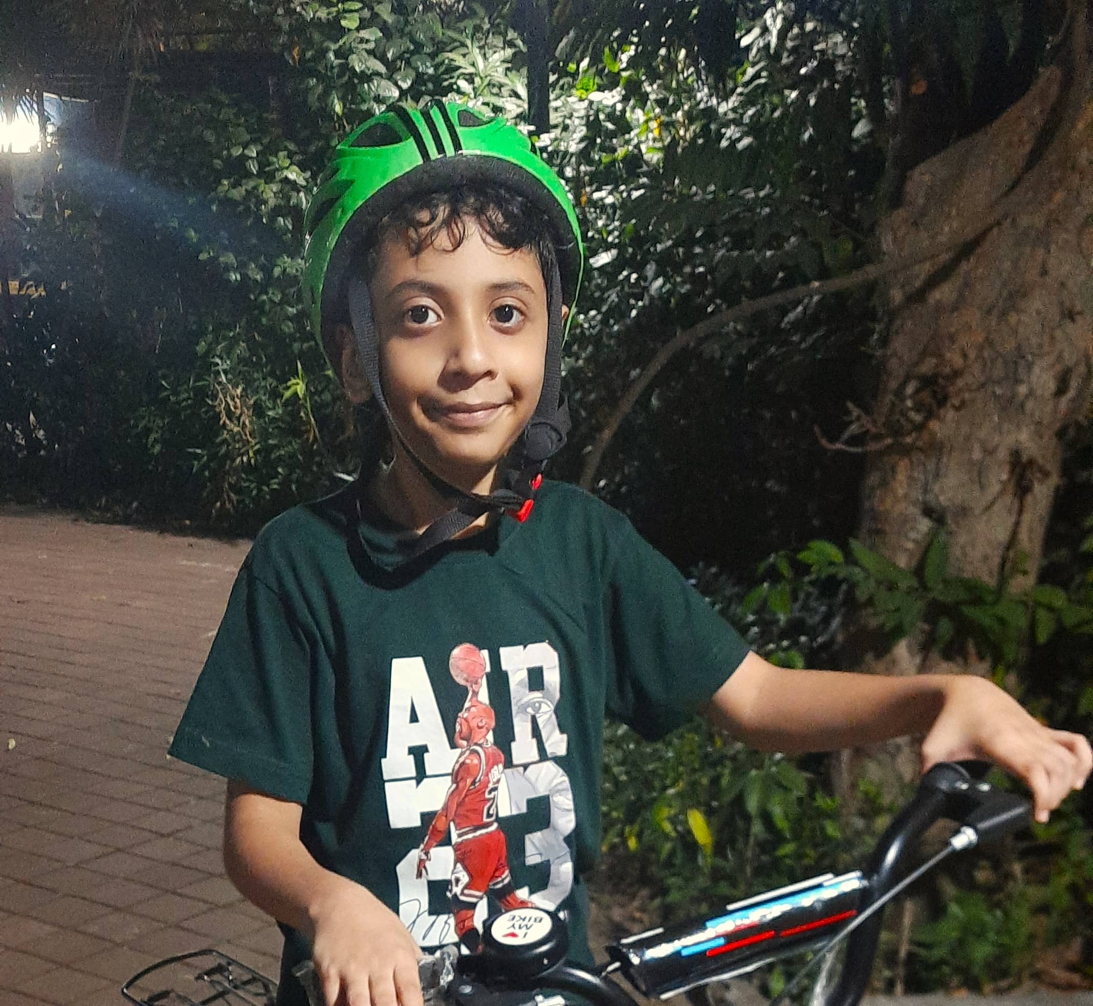 Small cute child wearing a green helmet, smiling for a pic